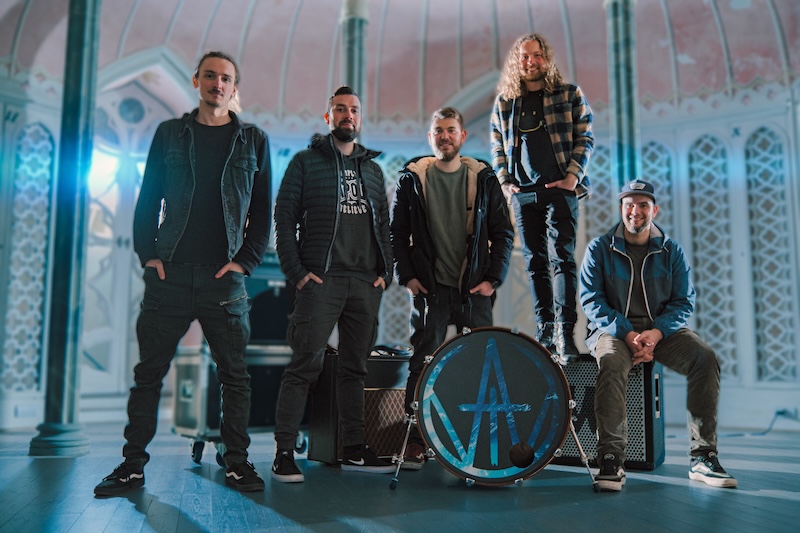 Young man with dark hair and beard, brown eyes, blue t-shirt